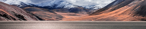 Horizontal road with snow-capped mountains in the background.